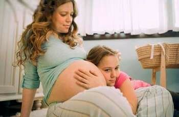 Девочка слушает живот беремнной мамы