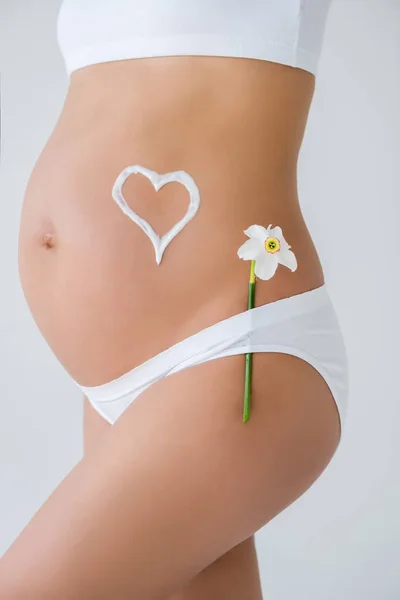 Беременный живот с цветком и сердца — стоковое фото