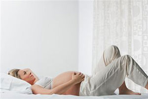 Беременная девушка лежит на кровати