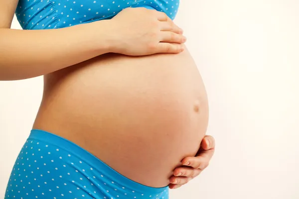 Молодая женщина, держа в руках беременный живот — стоковое фото