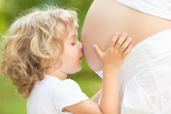Ребенок, целуя живот беременной женщины — стоковое фото