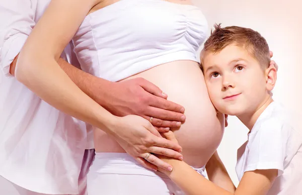 Счастливые семьи ждут ребенка. Детские прослушивания беременный живот — стоковое фото