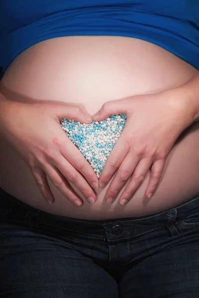 Беременность живот руками и синий рождения конфеты, создание АЭМ — стоковое фото