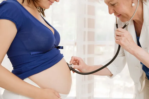 Беременная женщина и врач использует стетоскоп для прослушивания — стоковое фото
