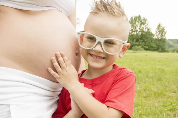 Мальчик прослушивания беременный живот — стоковое фото