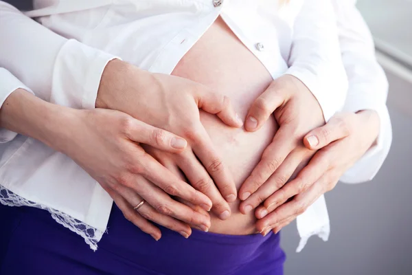 Беременная женщина с сердцем форму руки — стоковое фото