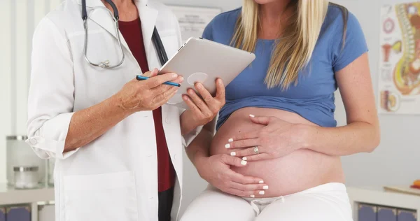 Беременная женщина и доктор при исполнении служебных обязанностей — стоковое фото