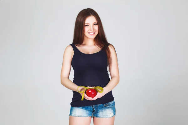 Беременная женщина с яблоком и измерительные ленты — стоковое фото