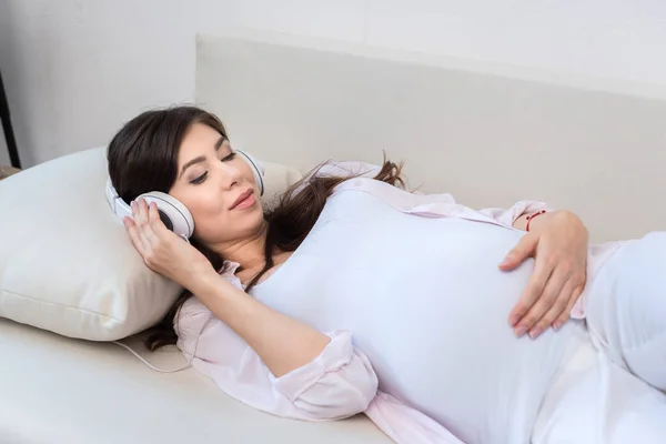 Беременная женщина в большие наушники — стоковое фото