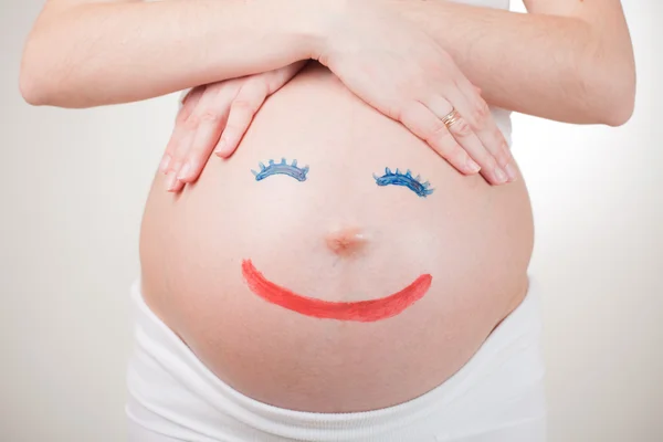 Рисование лиц на беременный живот — стоковое фото