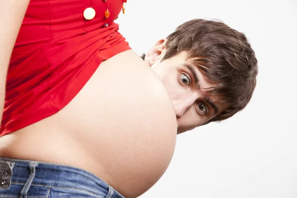 Удивлен человек заглядывать из-за беременный живот — стоковое фото