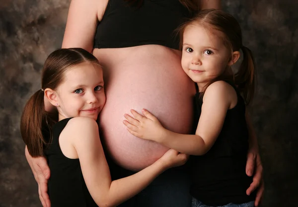 Беременный живот мамы и сестры — стоковое фото