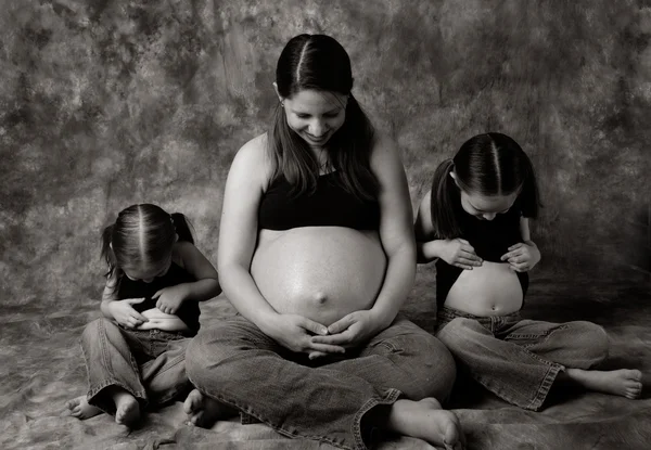 Беременная мама и маленьких девочек, сравнивая животы — стоковое фото