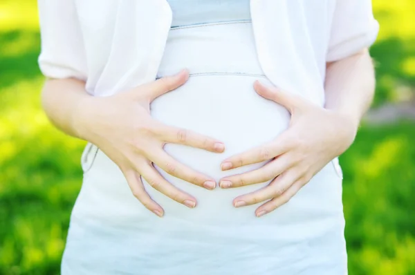 Руки на беременный живот — стоковое фото